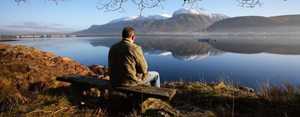 Man sitting on bench looking at Ben Nevis, Scotland