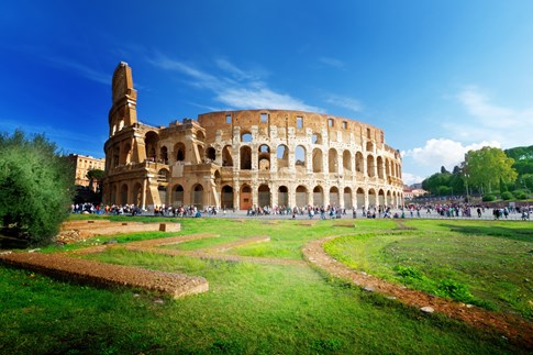 Roman Colosseum with blue sky and green grass, Rome, Italy