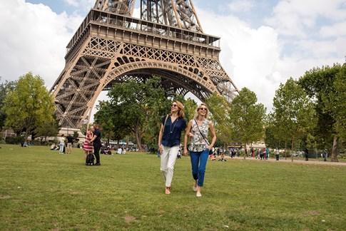 Two women walking at the base of the Eiffel Tower in Paris, France