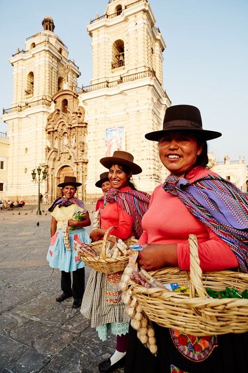 Peruvian women holding baskets outside church, Peru