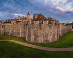 Book a guided tour with Grand European Travel and visit the Tower of London, a historic castle on the north bank of the River Thames in central London, featuring the White Tower built by William the Conqueror, surrounded by outer walls and fortifications, with the modern London skyline as a contrasting backdrop.
