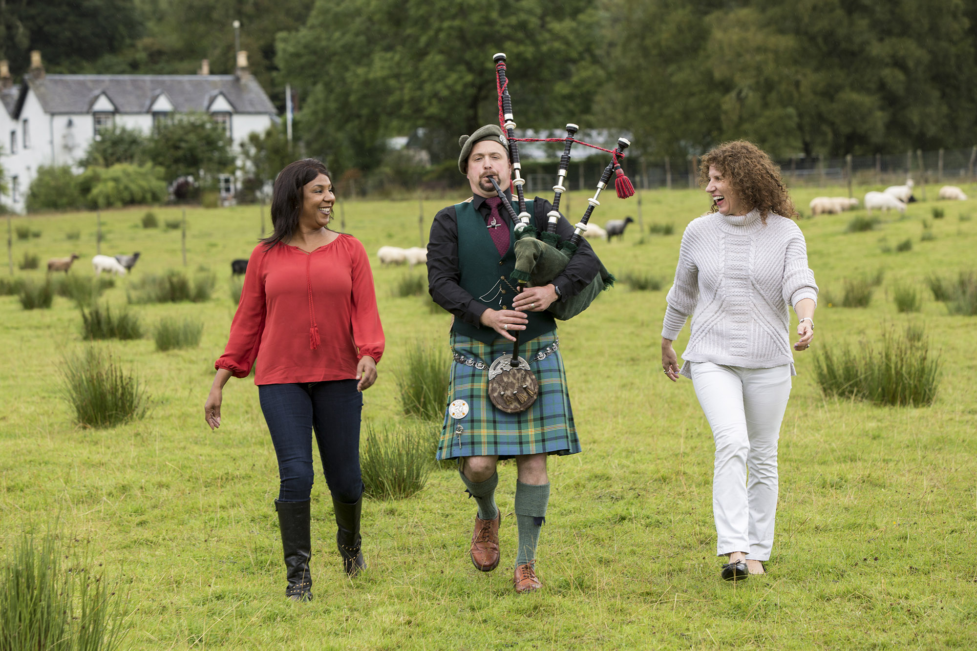 Scotland Bagpipe Tourists Walking With Piper On Green