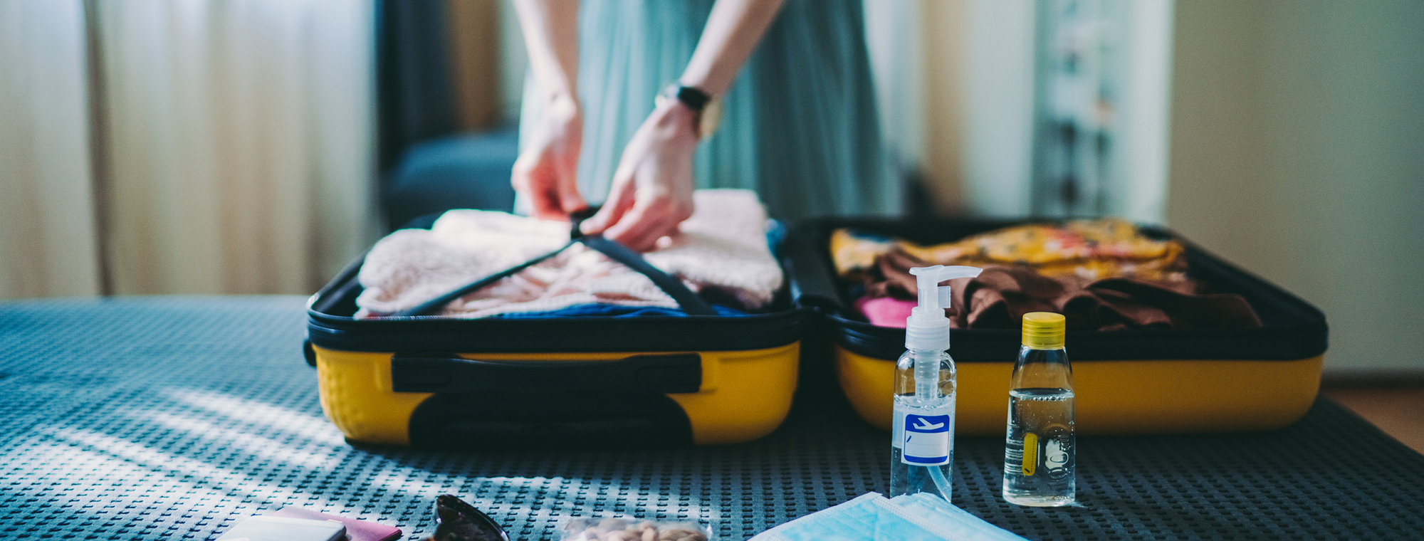 Expert Woman Packing Suitcase Sanitizer Toiletries Yellow Luggage Masks